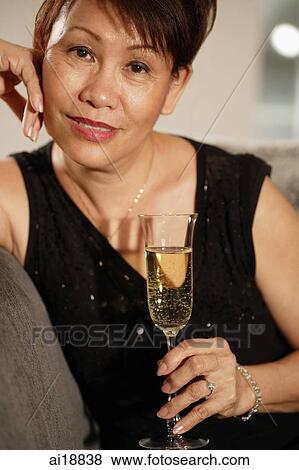 Mature woman holding glass of champagne, looking at camera View Large Photo Image Stock Photo - Mature woman holding glass of champagne, looking at camera. Fotosearch