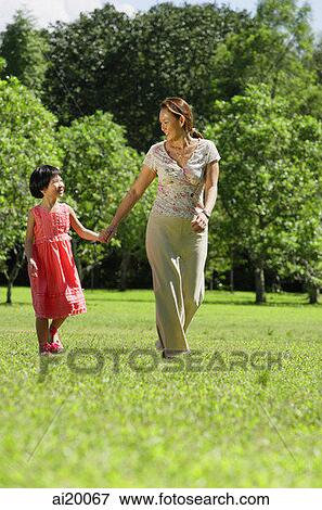 Mother and daughter, holding hands, walking on grass View Large Photo Image Stock Photo - Mother and daughter, holding hands, walking on grass. Fotosearch