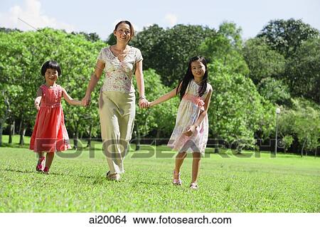 Mother and two daughters holding hands in park View Large Photo Image Picture - Mother and two daughters holding hands in park. Fotosearch