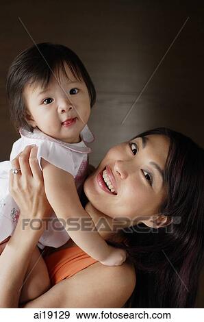 Mother carrying young daughter, smiling at camera View Large Photo Image Stock Photo - Mother carrying young daughter, smiling at camera. Fotosearch