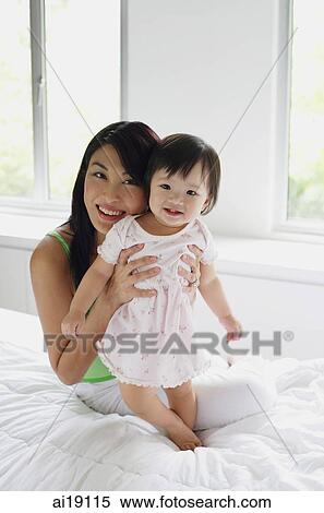 Stock Photography - Mother embracing baby girl, smiling at camera. Fotosearch