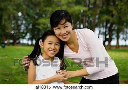 Mother embracing daughter, both smiling at camera View Large Photo Image Stock Photography - Mother embracing daughter, both smiling at camera. Fotosearch