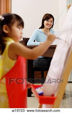Mother watching young girl painting on easel View Large Photo Image Stock Image - Mother watching young girl painting on easel. Fotosearch