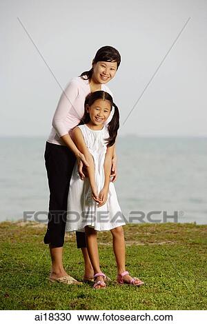 Mother with daughter, standing by beach, smiling at camera View Large Photo Image Stock Image - Mother with daughter, standing by beach, smiling at camera. Fotosearch