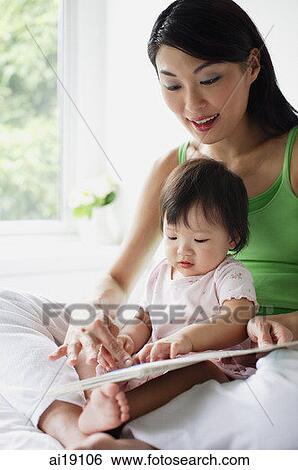Mother with young daughter, looking at book View Large Photo Image Stock Photograph - Mother with young daughter, looking at book. Fotosearch