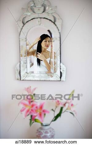 Stock Photo - Reflection in the mirror, woman touching her hair. Fotosearch