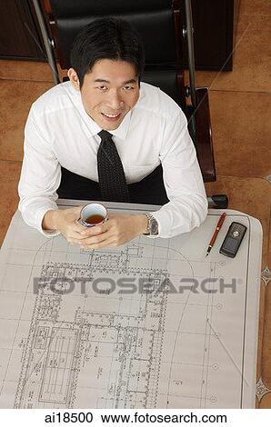 Seated businessman smiling at camera, high angle view View Large Photo Image Stock Image - Seated businessman smiling at camera, high angle view. Fotosearch