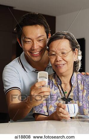 Senior woman and mature son looking at mobile phone View Large Photo Image Stock Photo - Senior woman and mature son looking at mobile phone. Fotosearch