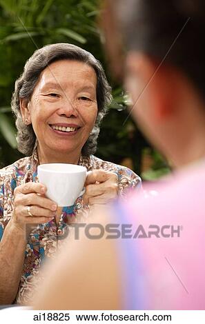 Senior woman holding cup, facing another person, over the shoulder view View Large Photo Image Stock Photography - Senior woman holding cup, facing another person, over the shoulder view. Fotosearch
