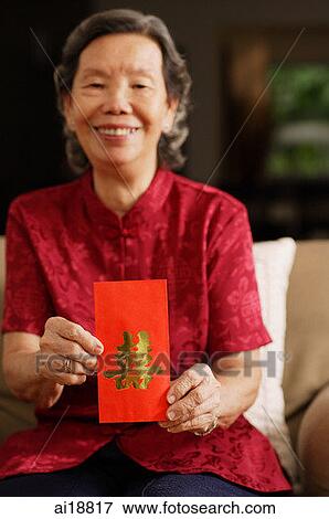 Senior woman holding red packet, smiling View Large Photo Image Stock Photo - Senior woman holding red packet, smiling. Fotosearch
