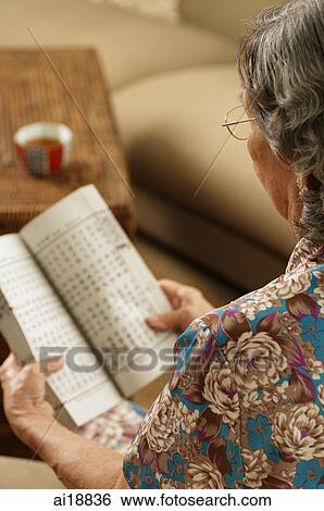 Stock Photograph - Senior woman reading a book, over the shoulder view. Fotosearch