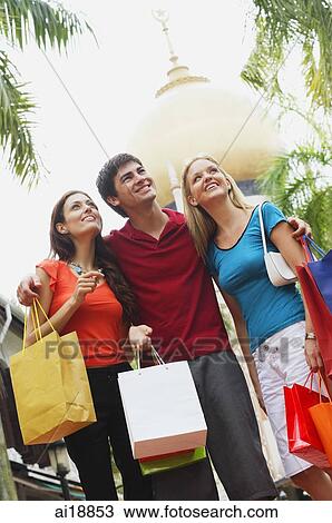 Stock Image - Three tourists having a picture taken, mosque in the background. Fotosearch