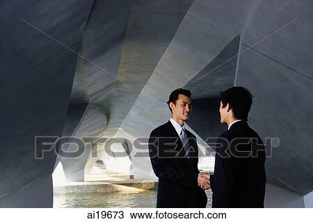 Two businessmen standing in tunnel structure, shaking hands View Large Photo Image Stock Image - Two businessmen standing in tunnel structure, shaking hands. Fotosearch