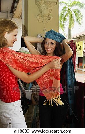 Two women shopping trying on shawls and scarves View Large Photo Image Stock Photo - Two women shopping trying on shawls and scarves. Fotosearch