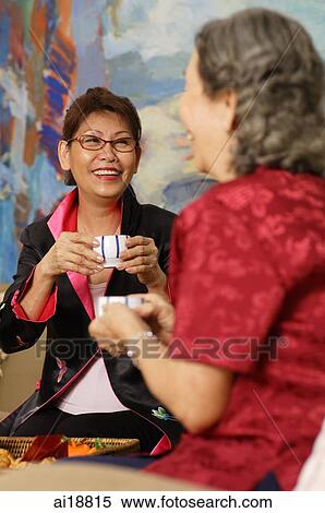 Two women sitting at home, having tea View Large Photo Image Stock Photography - Two women sitting at home, having tea. Fotosearch
