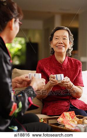Two women sitting in living room, having tea View Large Photo Image Stock Photograph - Two women sitting in living room, having tea. Fotosearch