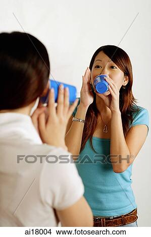 Two women talking using paper cup phone View Large Photo Image Picture - Two women talking using paper cup phone. Fotosearch