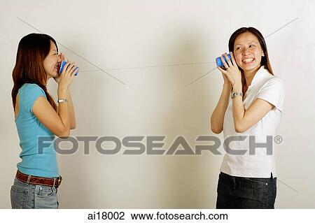 Two women using paper cup phone View Large Photo Image Stock Image - Two women using paper cup phone. Fotosearch