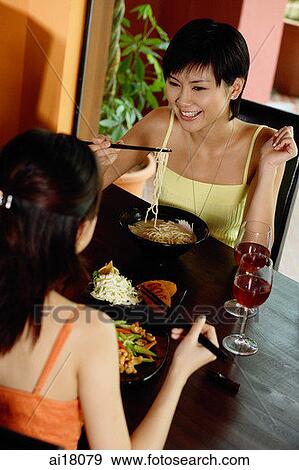 Stock Photo - Two young women having a meal in restaurant. Fotosearch