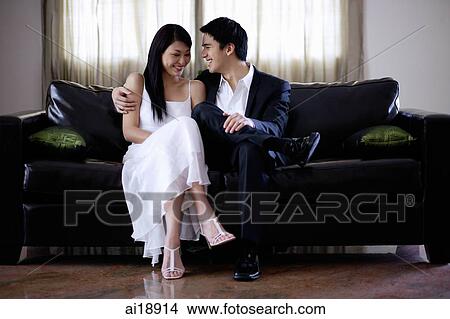 Well dressed couple sitting on sofa View Large Photo Image Picture - Well dressed couple sitting on sofa. Fotosearch