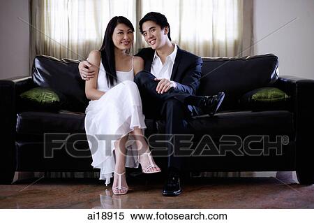 Well dressed couple sitting on sofa, smiling at camera View Large Photo Image Stock Photography - Well dressed couple sitting on sofa, smiling at camera. Fotosearch
