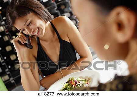 Stock Photo - Woman at restaurant table, using mobile phone. Fotosearch