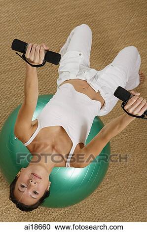 Woman balancing on fitness ball, holding dumbbells View Large Photo Image Stock Image - Woman balancing on fitness ball, holding dumbbells. Fotosearch