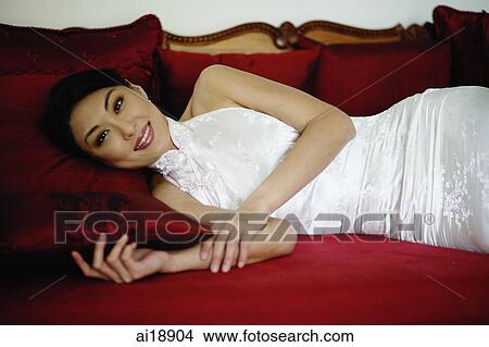 Woman dressed in Chinese cheongsam, lying on red sofa View Large Photo Image Picture - Woman dressed in Chinese cheongsam, lying on red sofa. Fotosearch
