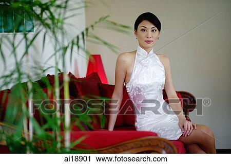 Woman dressed in white Chinese cheongsam, sitting on red sofa View Large Photo Image Stock Image - Woman dressed in white Chinese cheongsam, sitting on red sofa. Fotosearch