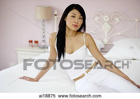 Woman dressed in white sitting on bed, looking at camera View Large Photo Image Stock Photography - Woman dressed in white sitting on bed, looking at camera. Fotosearch