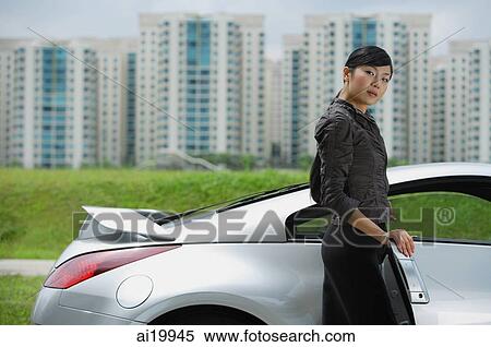 Woman getting into silver sports car, looking at camera View Large Photo Image Stock Photography - Woman getting into silver sports car, looking at camera. Fotosearch