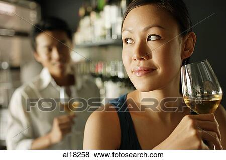Woman holding a drink, man in background View Large Photo Image Stock Photo - Woman holding a drink, man in background. Fotosearch