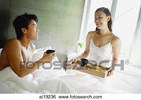 Woman holding breakfast tray, man sitting in bed View Large Photo Image Stock Photograph - Woman holding breakfast tray, man sitting in bed. Fotosearch