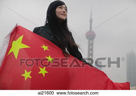 Stock Image - Woman holding China flag, Oriental Pearl TV Tower in the background. Fotosearch