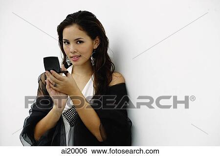 Stock Photograph - Woman holding compact, looking at camera. Fotosearch