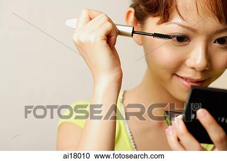 Woman holding compact mirror, applying mascara View Large Photo Image Stock Image - Woman holding compact mirror, applying mascara. Fotosearch
