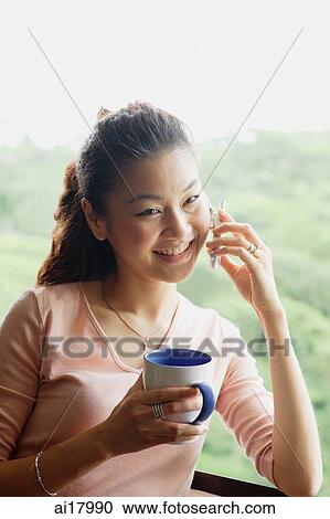 Woman holding mug and using mobile phone View Large Photo Image Stock Image - Woman holding mug and using mobile phone. Fotosearch