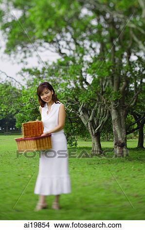 Picture - Woman holding picnic basket, smiling. Fotosearch