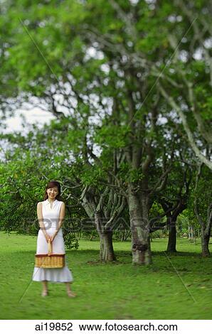 Woman holding picnic basket, standing in park View Large Photo Image Stock Image - Woman holding picnic basket, standing in park. Fotosearch