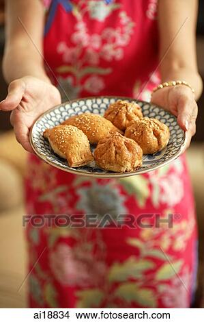 Woman holding plate of Chinese pastries, cropped image View Large Photo Image Picture - Woman holding plate of Chinese pastries, cropped image. Fotosearch