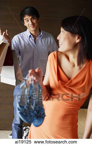 Woman holding shoes, looking over shoulder at man View Large Photo Image Stock Photography - Woman holding shoes, looking over shoulder at man. Fotosearch