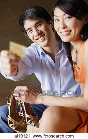 Woman holding shoes, man holding credit card, looking at camera View Large Photo Image Stock Image - Woman holding shoes, man holding credit card, looking at camera. Fotosearch