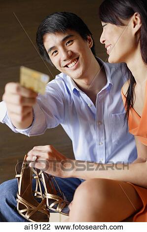 Woman holding shoes, man holding credit card towards camera View Large Photo Image Stock Image - Woman holding shoes, man holding credit card towards camera. Fotosearch