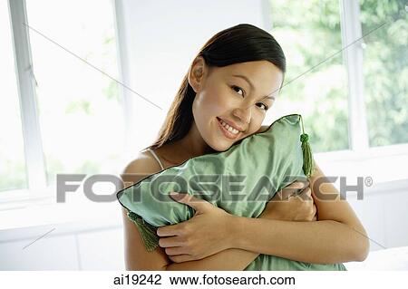 Woman hugging green cushion, smiling at camera View Large Photo Image Stock Image - Woman hugging green cushion, smiling at camera. Fotosearch