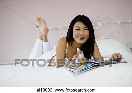 Woman in bedroom, flipping through magazine, smiling at camera View Large Photo Image Stock Image - Woman in bedroom, flipping through magazine, smiling at camera. Fotosearch