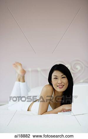 Woman in bedroom, using laptop, smiling at camera View Large Photo Image Stock Image - Woman in bedroom, using laptop, smiling at camera. Fotosearch