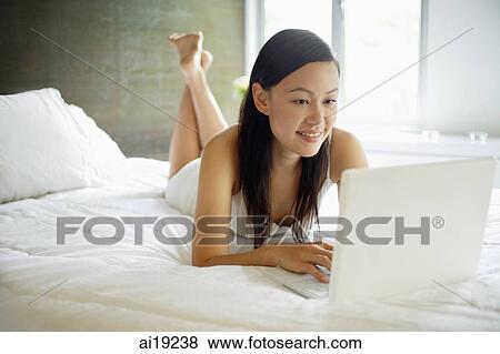 Woman in bedroom, using laptop View Large Photo Image Stock Photo - Woman in bedroom, using laptop. Fotosearch