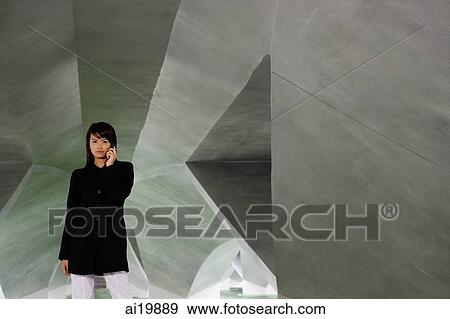Stock Photo - Woman in black jacket, using mobile phone. Fotosearch