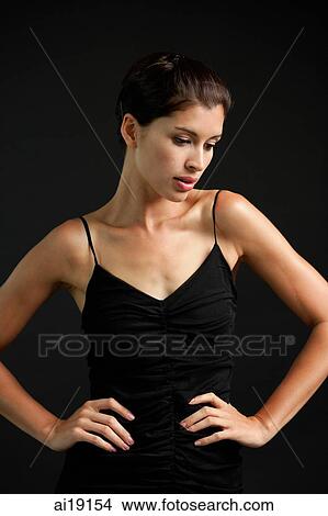 Picture - Woman in black tank top, hands on waist, looking down. Fotosearch