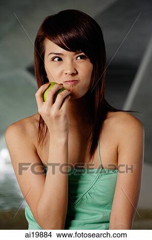 Woman in green top holding green apple, making a face View Large Photo Image Picture - Woman in green top holding green apple, making a face. Fotosearch